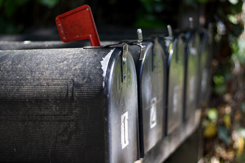 A line of black mailboxes wait for printed newsletters